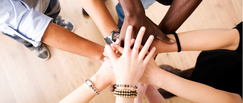 mãos de pessoas multiétnicas simbolizando a colaboração entre as pessoas